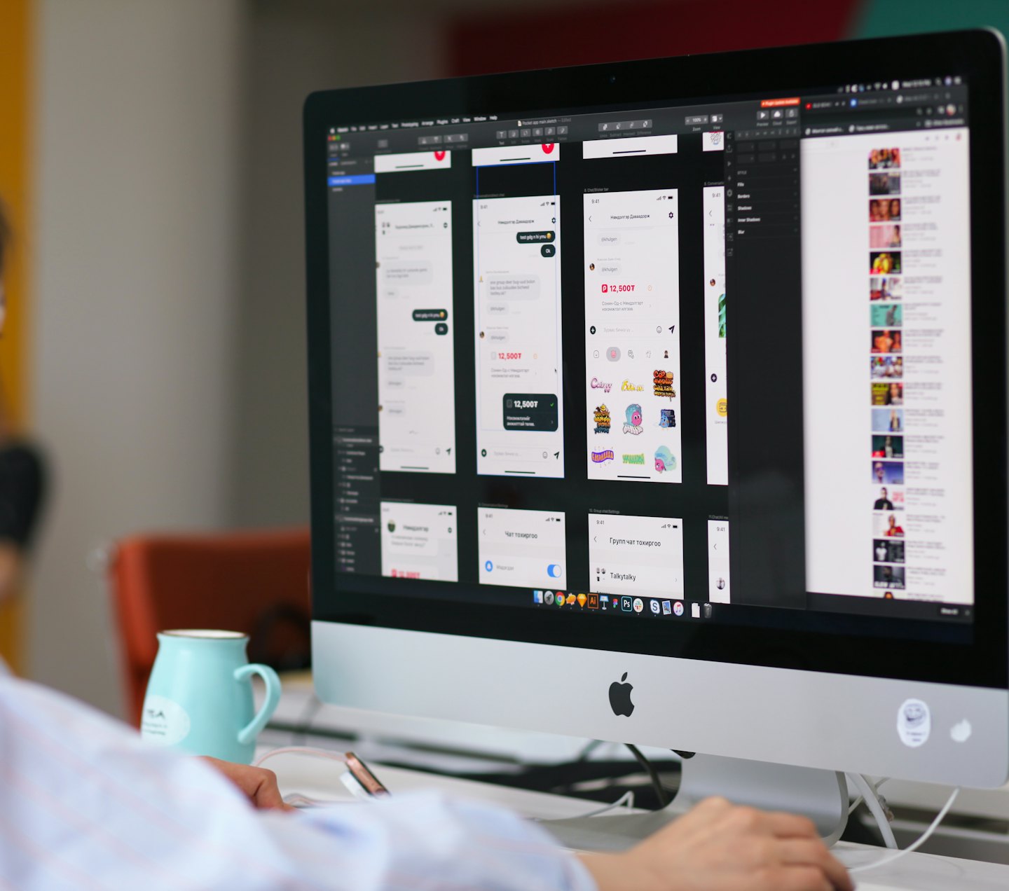 Persona che progetta wireframe di app su un computer desktop con una tazza verde acqua.